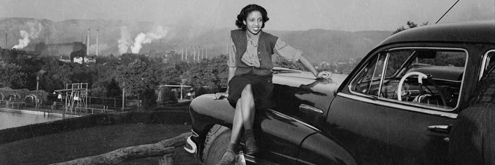 Charles “Teenie” Harris, Doris Clark (Moody) seated on Buick car with steel mill in background, Clairton (detail), ca. 1945, Teenie Harris Archive, Carnegie Museum of Art