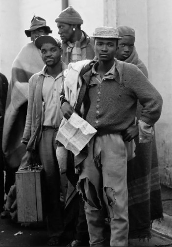 Pensive tribesmen, newly recruited to mine labour, awaiting processing and assignment, South Africa, 1960s. (c) Ernest Cole / Magnum Photos