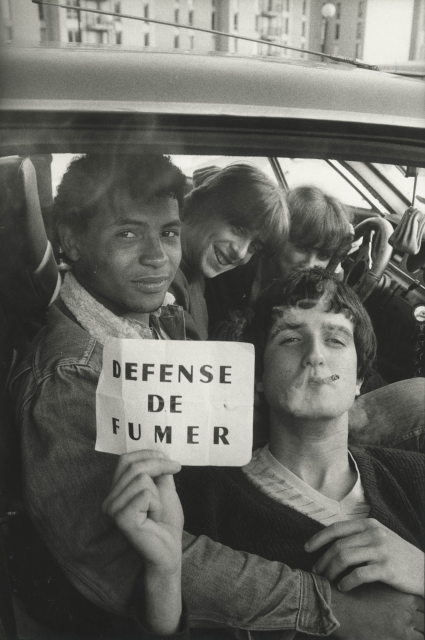 Sabine Weiss (1924-2021), Jeunes gens fumant dans une voiture et tenant un écriteau « DÉFENSE DE FUMER », Carros, 20 avril 1983  © Les Arts Décoratifs / photo : Christophe Dellière